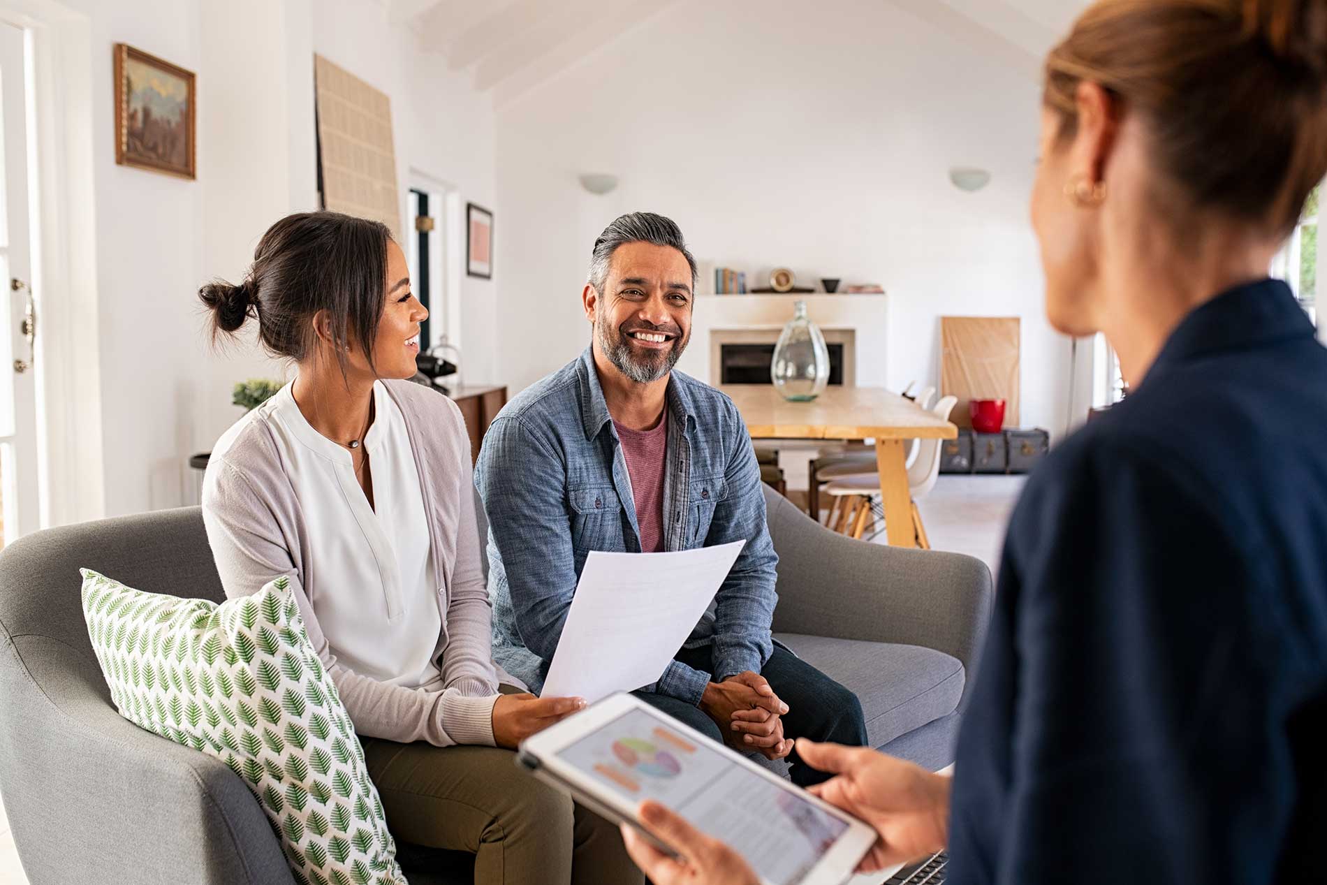Couple smiling as they talk through their financial plan with an adviser at home