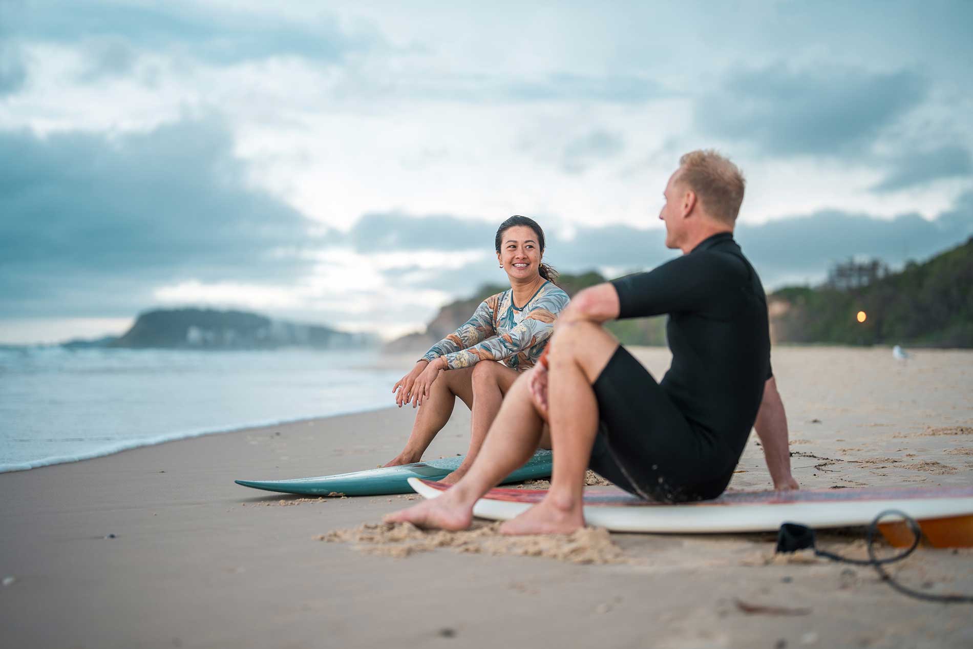 Couple relaxing on the beach with their surfboards after a morning surf