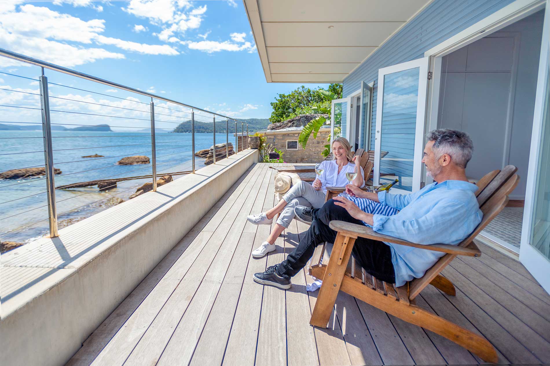 Couple relaxing with a glass of wine on the deck of their waterfront home