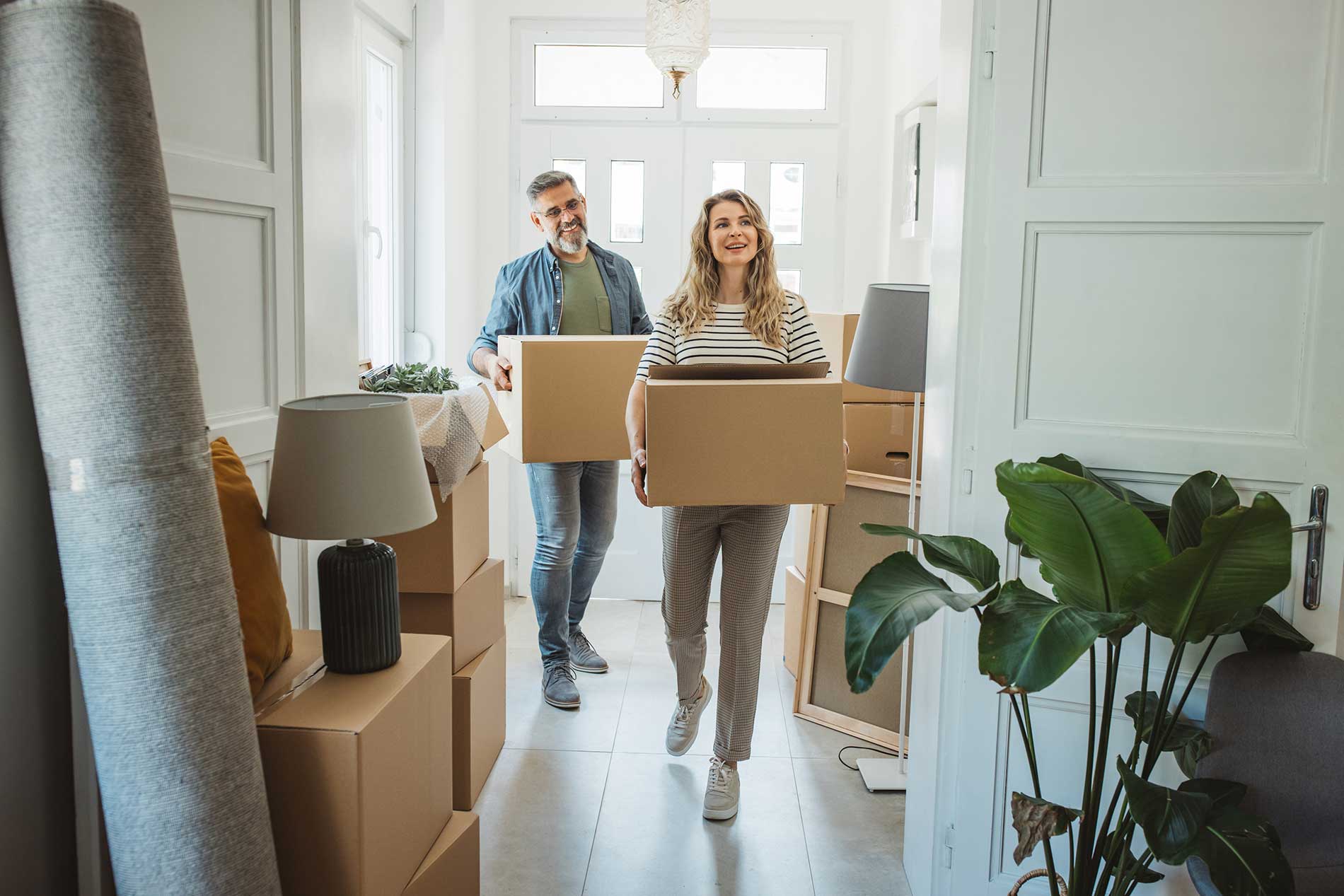 Family on the couch among moving boxes, holding a cardboard roof over their heads