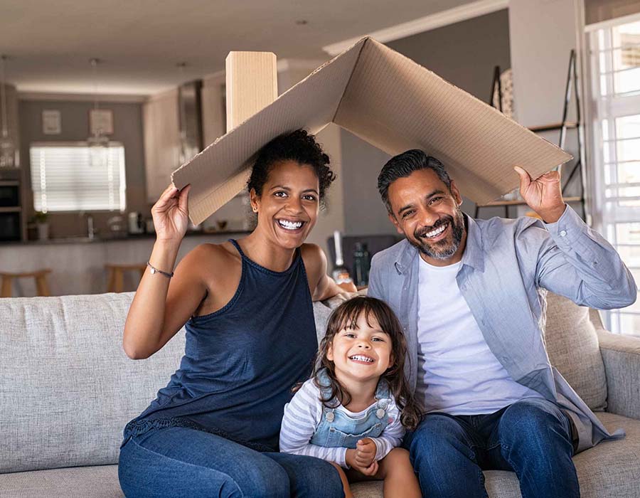 Smiling family sheltering under a cardboard roof at home